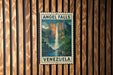 A vintage-style metal sign with the text "ANGEL FALLS VENEZUELA" and a painting of a waterfall, mounted on a wooden wall.