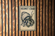 A sign with the text "HERMIT CRAB" and an illustration of a hermit crab is displayed on a wooden wall.