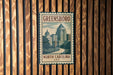A vintage-style metal sign with the text "GREENSBORO NORTH CAROLINA USA" displayed on a wooden wall.