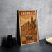 A vintage-style metal sign with the text "VARANASI INDIA" and an illustration of a temple or palace, along with a boat in the water, is displayed on a gray concrete surface.