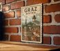 A vintage postage stamp depicting the town of Graz, Austria, with a church spire and other buildings in the background.