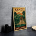 A vintage-style metal sign with a tropical island and temple illustration, featuring the word "KANDY" at the top.