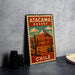 A vintage-style metal sign with a desert landscape and a mountain, featuring the text "ATACAMA DESERT CHILE" and a postage stamp-like border.