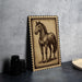 a framed illustration of a horse, which is placed on a surface next to some black camera lenses.