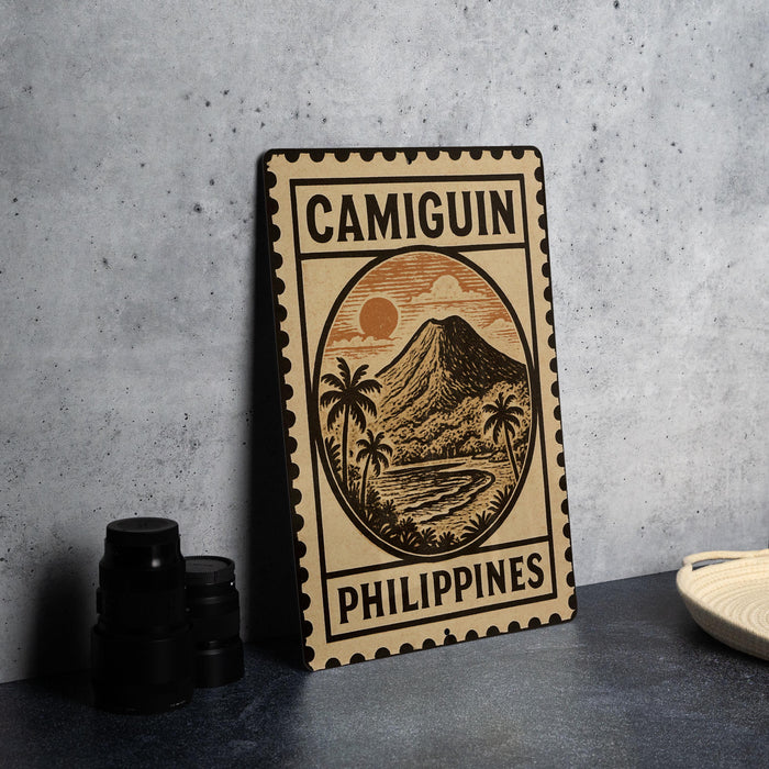 a metal sign with a tropical landscape and palm trees, along with the text "CAMIGUIN PHILIPPINES".