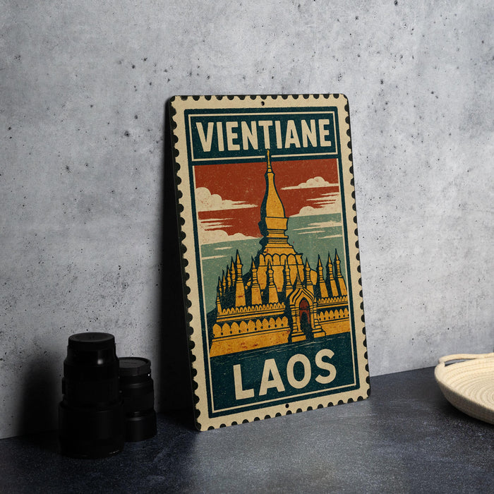 A vintage-style metal sign with a colorful illustration of a temple, placed on a gray surface next to some black camera lenses.