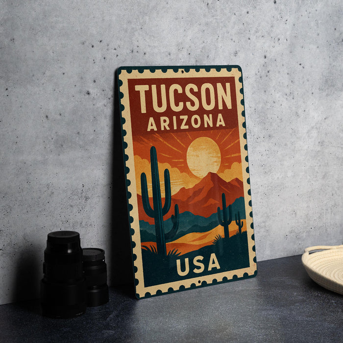 A vintage-style metal sign with the text "Tucson, Arizona USA" printed on it, featuring a desert landscape with cacti and mountains.