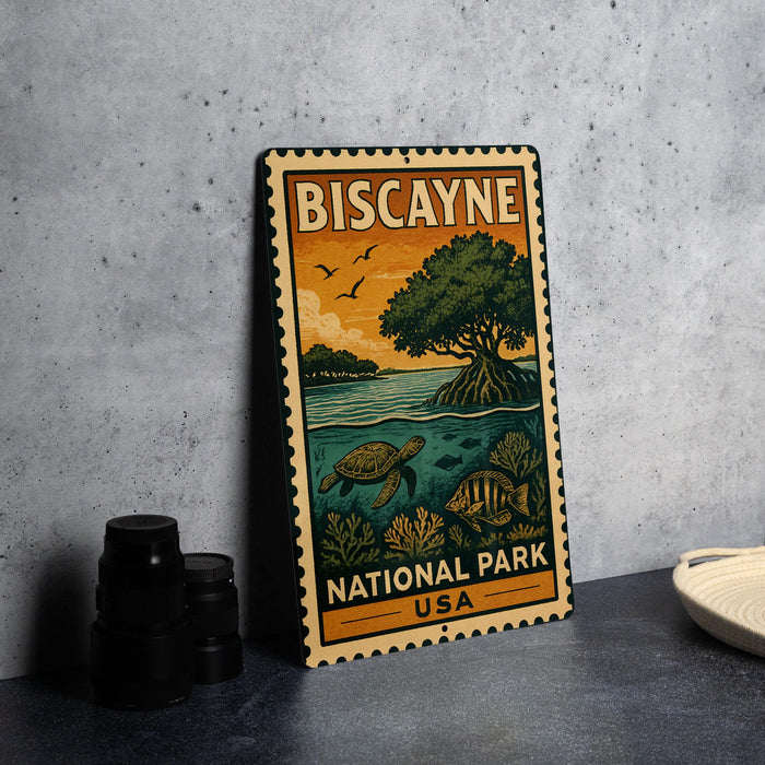 A vintage-style metal sign for Biscayne National Park in the USA, featuring an illustration of a tropical landscape with a tree, sea turtle, and fish.