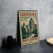 A vintage-style metal sign with the text "GREENSBORO NORTH CAROLINA USA" and an illustration of a cityscape, placed on a gray countertop next to some black camera lenses.