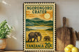 A vintage-style stamp depicting an elephant and a baby elephant in a grassy landscape, with mountains in the background and a sun in the sky. The stamp is framed with a border and has text that reads "NGORONGOORO CRATER TANZANIA 20c".