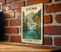 A framed postcard depicting a scenic waterfall in the Jiuzhaigou Valley, with mountains in the background.