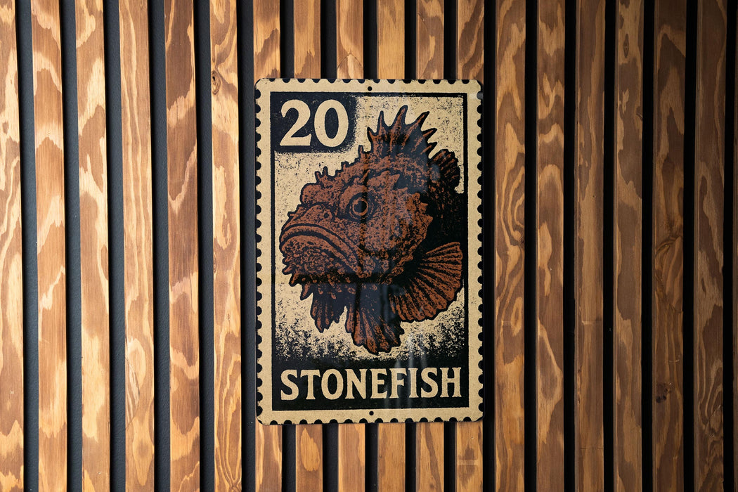 A metal stamp with a fish image and the number 20 on it, mounted on a wooden wall.