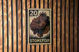 A metal stamp with a fish image and the number 20 on it, mounted on a wooden wall.