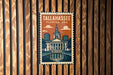 A metal sign with a vintage-style illustration of Tallahassee, Florida, USA, mounted on a wooden wall.