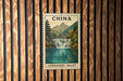 A postage stamp depicting a scenic waterfall in the JIUZHAI GOU VALLEY, China, hanging on a wooden wall.