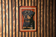 A metal sign featuring a black and brown dog's portrait is displayed on a wooden wall.