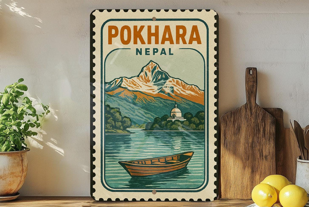 A vintage-style metal sign with a mountain landscape and a boat, mounted on a wall next to a wooden cutting board and some potted plants.