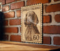 A wooden table with a framed image of a dog, which appears to be a postage stamp or a decorative piece, mounted on a brick wall.