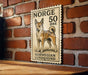 A wooden surface with a framed image of a dog, which appears to be a postage stamp from Norway.