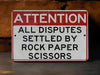 a red and white sign that says attention all disputes settled by rock