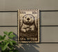 A metal sign featuring a sea otter, with a US 10¢ postage stamp on the back.