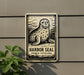 a sign with a seal illustration, mounted on a wall next to a plant.