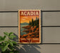 A vintage-style sign for Acadia National Park in the United States, featuring a scenic landscape with pine trees, rocky cliffs, and a sunset over the water.