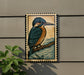 a framed illustration of a colorful bird perched on a branch, set against a textured background.