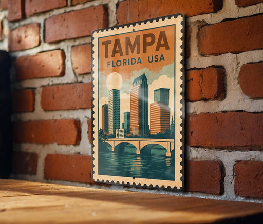 A vintage-style poster of Tampa, Florida, USA, featuring a cityscape with a bridge and water, mounted on a brick wall.