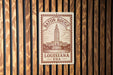A metal sign with the text "Baton Rouge, Louisiana, USA" printed on it, mounted on a wooden wall.