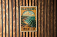 A vintage-style travel poster for the island of Isla Mujeres, Mexico, featuring a scenic landscape with a desert and ocean.