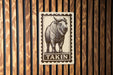 a wooden wall with a metal sign featuring a drawing of a bison or ox with the word "Takin" written below it.