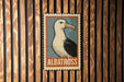 A vintage-style metal stamp featuring a seagull is displayed on a wooden wall.