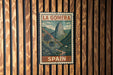 A vintage-style metal sign with the text "LA GOMERA" and "SPAIN" printed on it, hanging on a wooden wall.