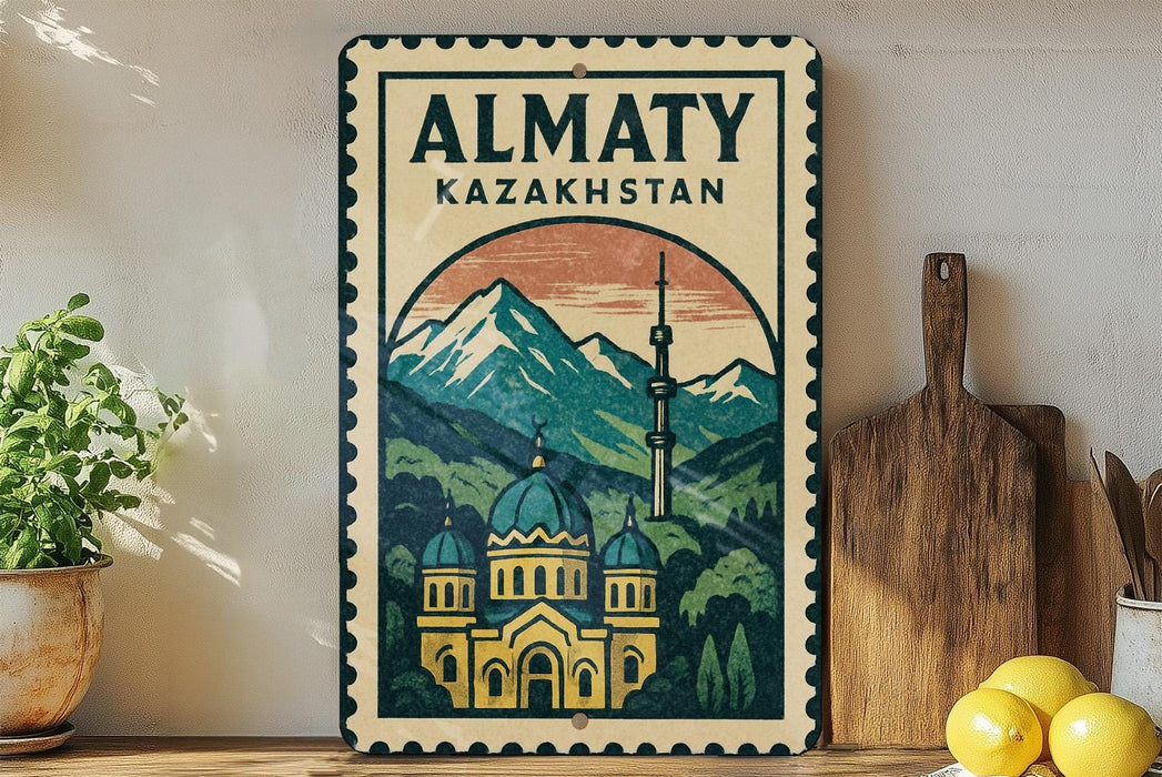 a vintage-style sign for Almaty, Kazakhstan, with a mountain landscape and a domed building in the center. The sign is displayed on a wall, with a wooden cutting board and a potted plant to the left.