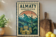 a vintage-style sign for Almaty, Kazakhstan, with a mountain landscape and a domed building in the center. The sign is displayed on a wall, with a wooden cutting board and a potted plant to the left.