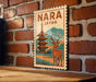 A vintage-style poster of a temple with a deer in the foreground, mounted on a brick wall.