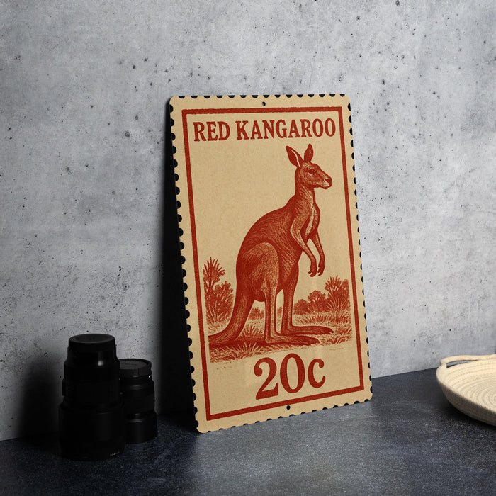 A red kangaroo stamp with the text "RED KANGAROO" and "20c" printed on it, placed on a gray surface next to some black camera lenses.