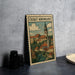 A metal sign with a vintage illustration of a town, featuring a castle, buildings, and a river, is displayed on a table.