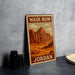A metal sign with a desert landscape and mountains, featuring the text "Wadi Rum Jordan" on it, is displayed on a table next to some black camera lenses.