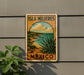 A vintage-style sign for "Isla Mujeres, Mexico" is displayed on a wall, featuring a scenic landscape with a desert and ocean.