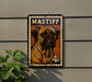 A metal sign featuring a dog illustration and the text "MASTIFF" is mounted on a wall, with a plant visible to the left.