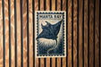 A metal plate with a printed image of a manta ray, which is a type of ray, is mounted on a wooden wall.
