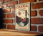 A vintage-style metal sign with the text "CHANIA GREECE" and an illustration of a lighthouse and a cityscape, mounted on a brick wall.