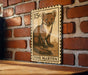 A wooden table with a framed image of a pine marten on it, mounted on a brick wall.
