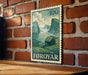 A wooden table with a framed image of a rural landscape, depicting a small house and mountains, mounted on a brick wall.