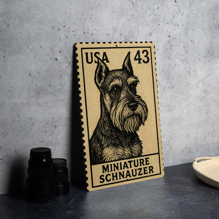 A miniature schnauzer dog stamp is displayed on a table, with a stack of black camera lenses and a white dish nearby.