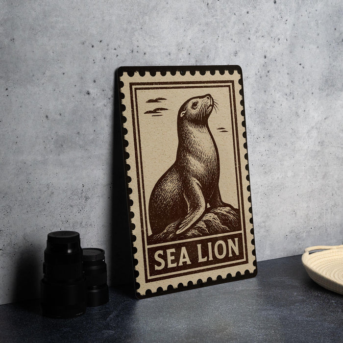 A framed illustration of a sea lion is displayed on a wall, with a stack of black camera lenses to the left and a white plate to the right.