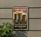 A vintage-style metal sign with a cityscape and a bridge, mounted on a wall, with a plant to the left.