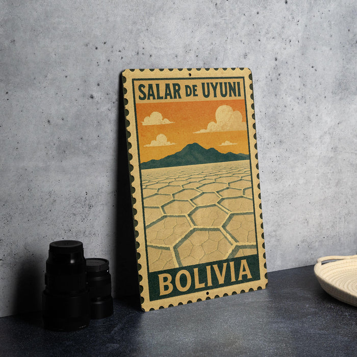 A vintage-style metal sign with the text "Salar de Uyuni Bolivia" printed on it, depicting a desert landscape with mountains in the background.